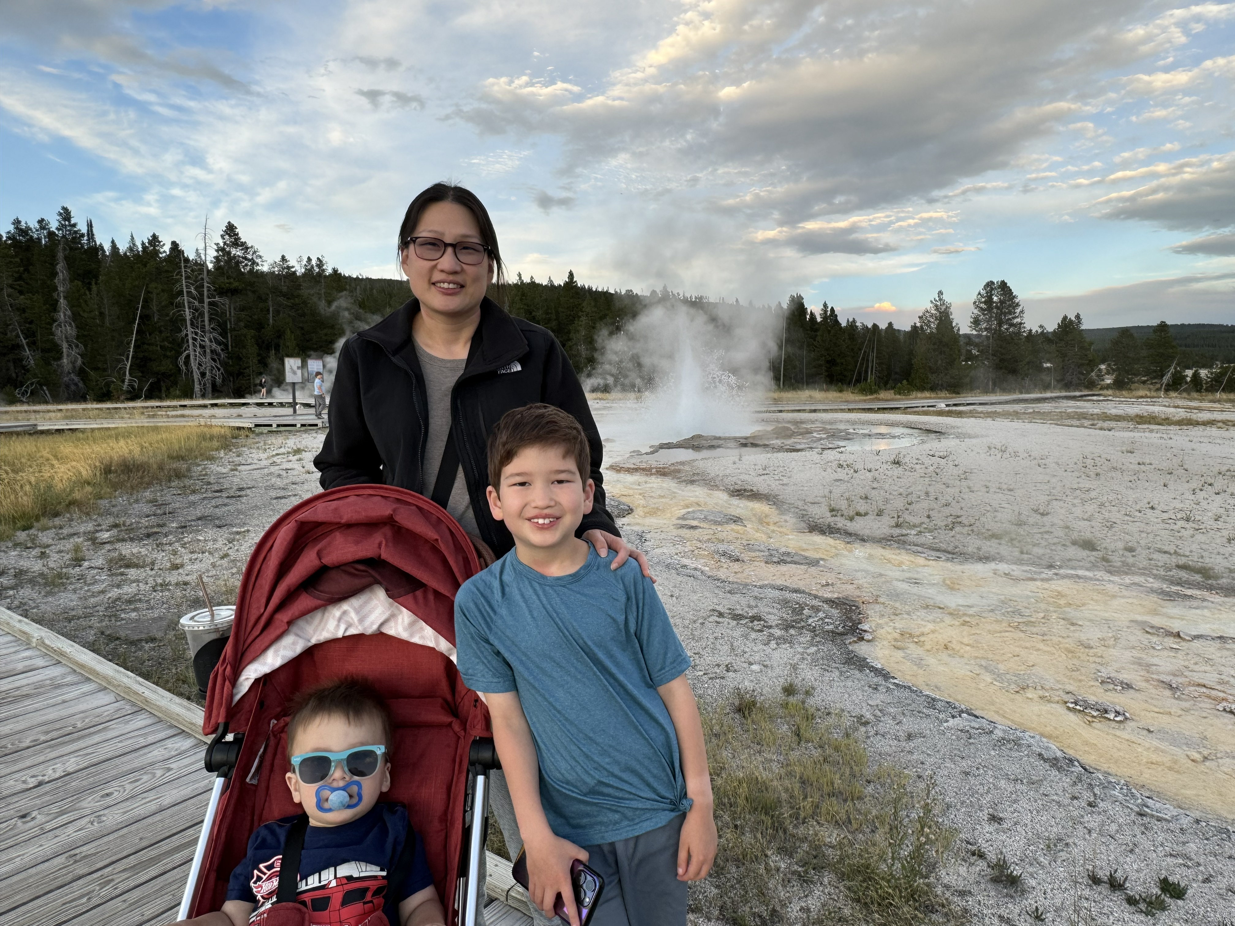 AwomanandtwoyoungboysposeinfrontofthebubblingmudpotsinYellowstoneNationalPark