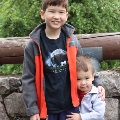 Twoyoungboyssmileandstandinfrontofastonewall