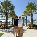 DrEgalkaandhiswifestandinfrontofpalmtreesandtheocean