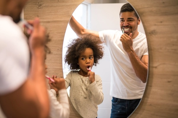 Father and daughter brush teeth together