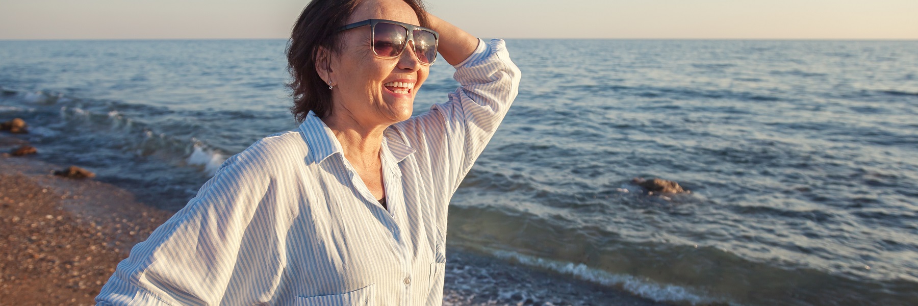 Maturewomanenjoyingsunsetatthecoast