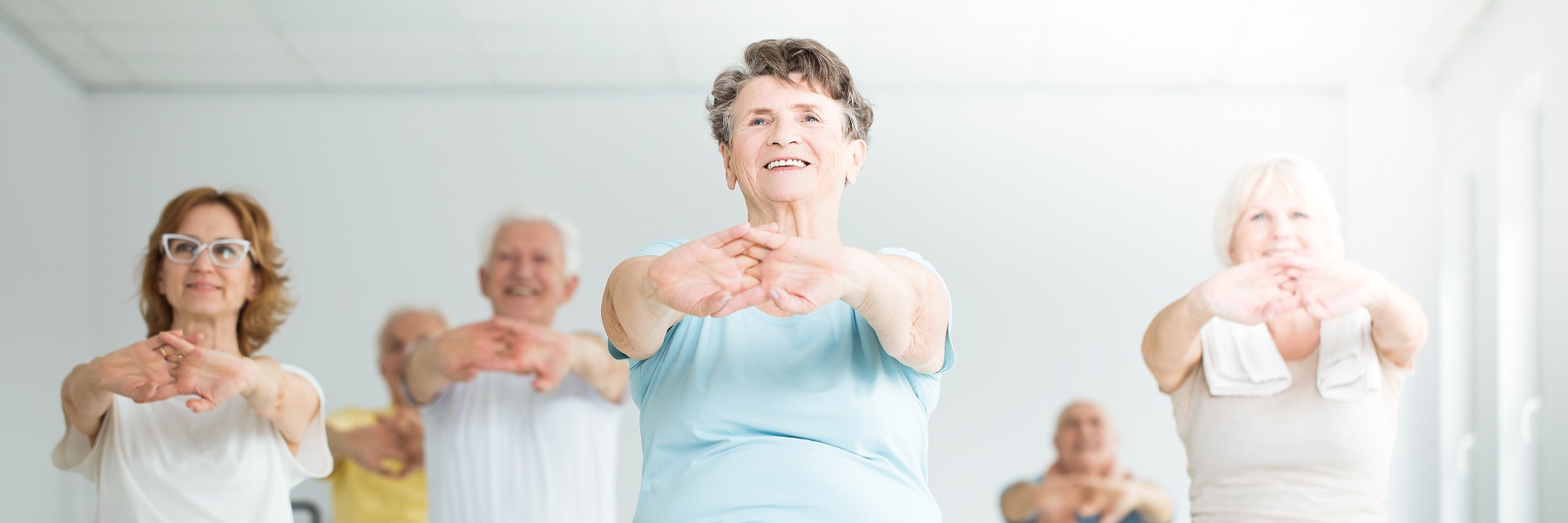 Smilingelderlywomanstretchingingentleyogaclass