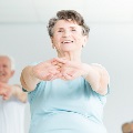 Smilingelderlywomanstretchingingentleyogaclass