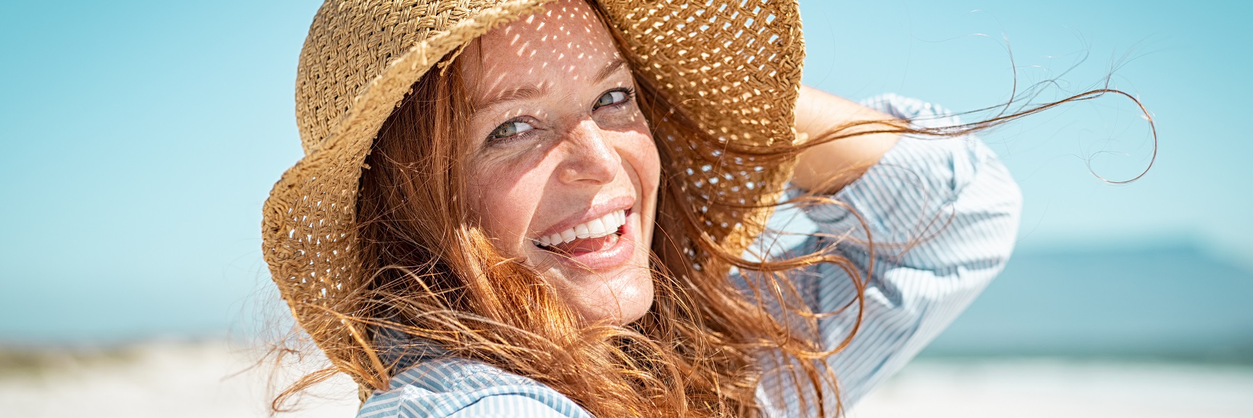 Smilingmaturewomanonthebeachwithastrawhat