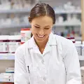 Ayoungwomanpharmacistinawhitecoatassistsandelderlymanattheretailcounter