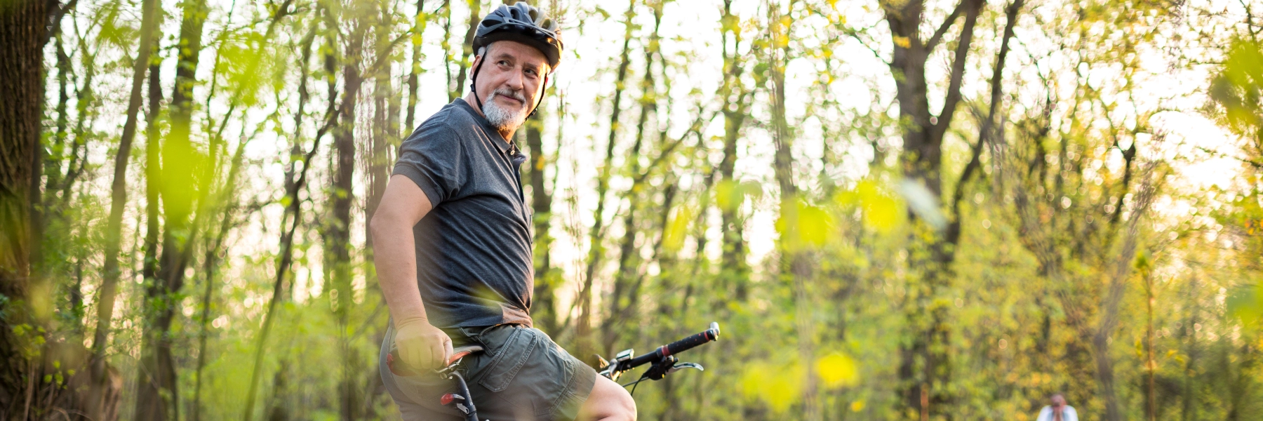 Middleagedmanridingabikethroughthewoods