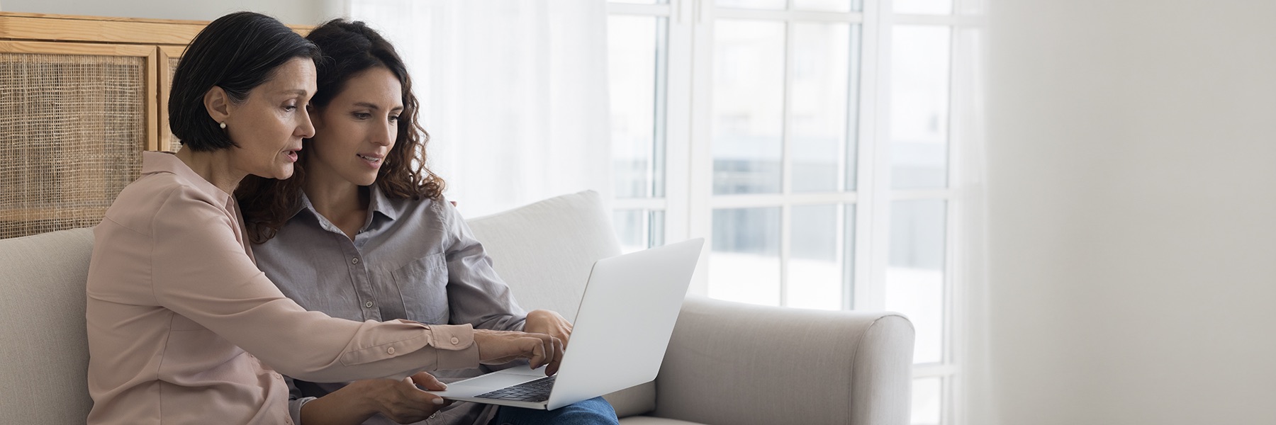 Womanandadultdaughtersittingandlookingatalaptopcomputer