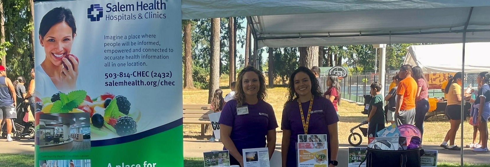 TwoSalemHealthCHECstaffersstandingbehindinformationtableatacommunityevent