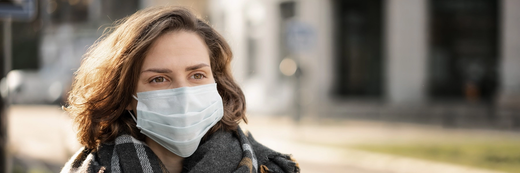 Awomaninwintercoatandscarfwearingasurgicalmask