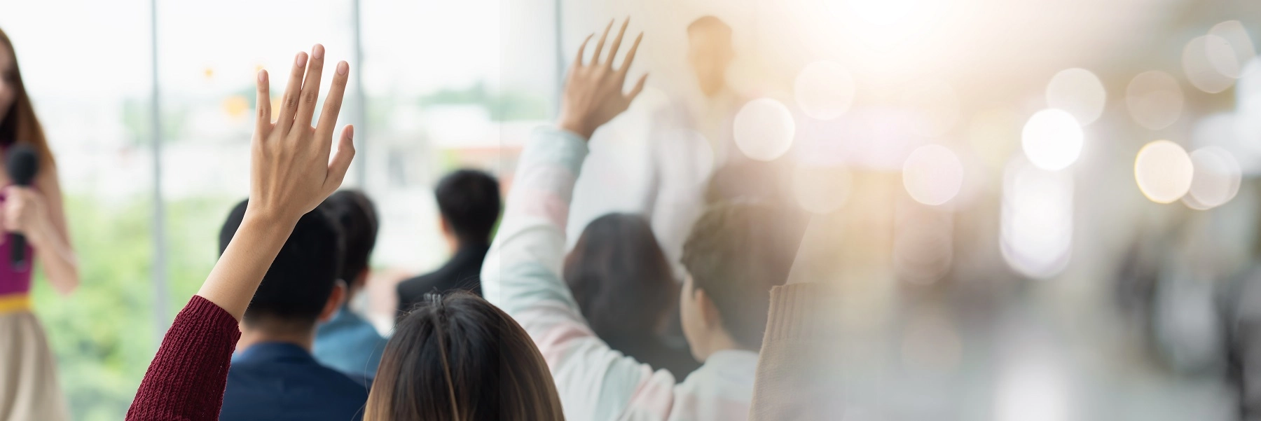 Blurredstockimageofadultlearnersrisinghandsinagrouptrainingsession
