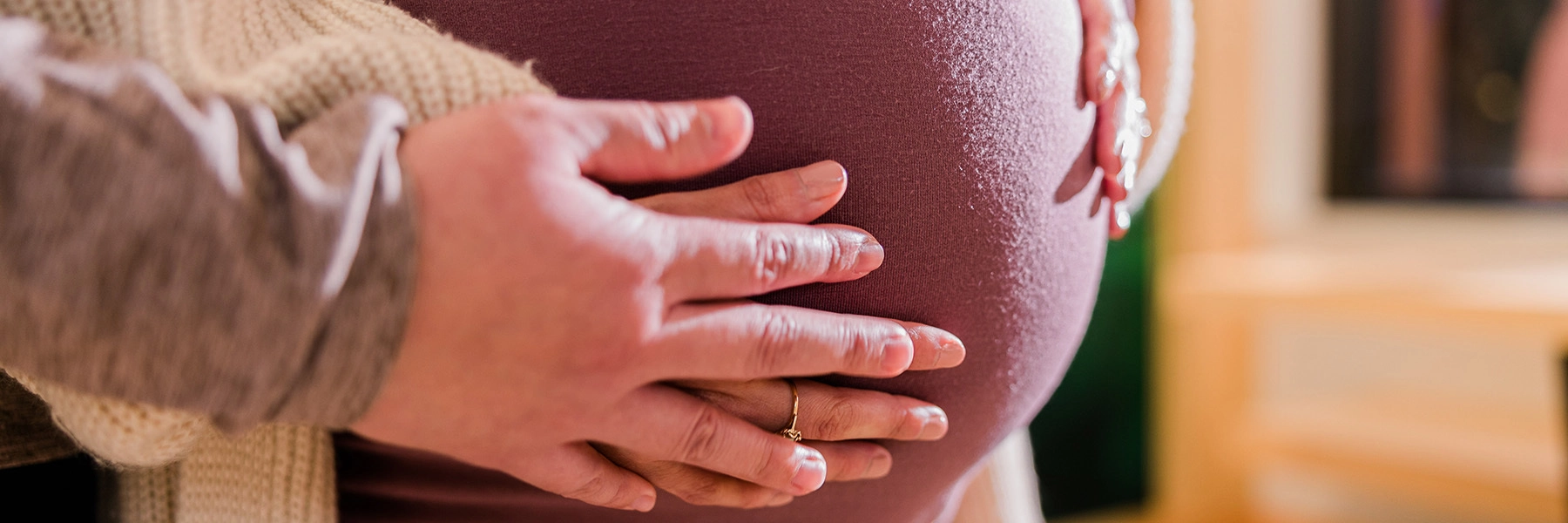 Handsonapinkshirtstretchedoverapersonsbelly