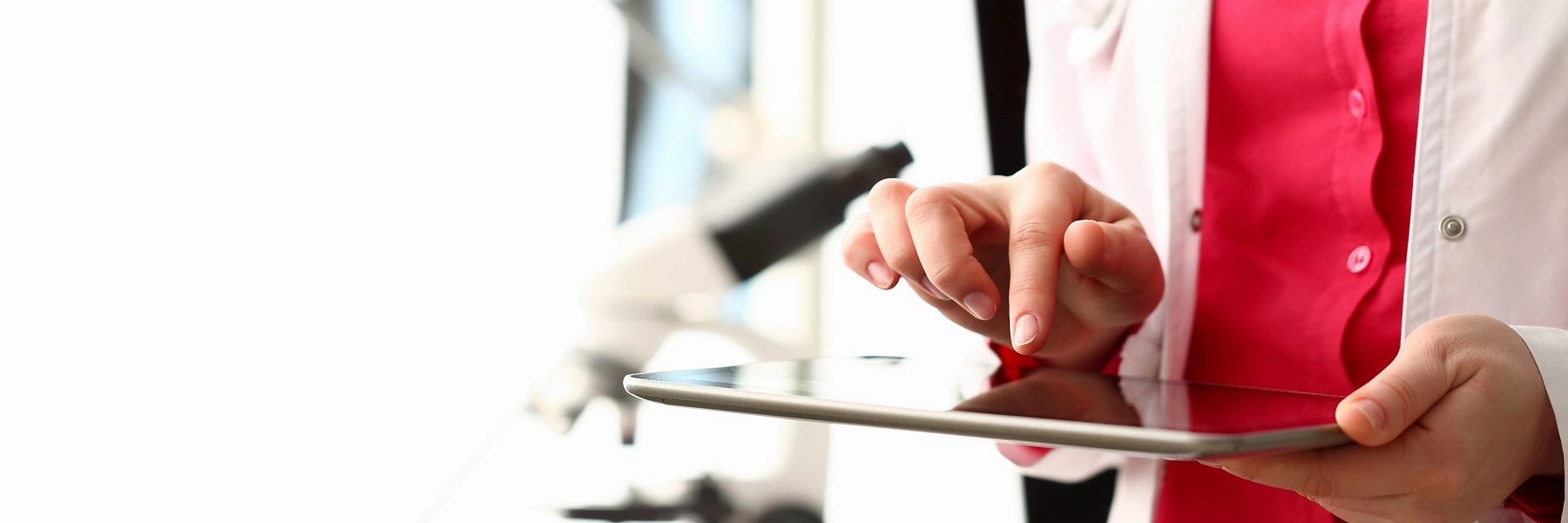 Ahandwearingawhitelabcoatholdingatabletshowinganx-ray