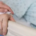 Avisitorholdsthehandofanelderlypatientinahospitalbed