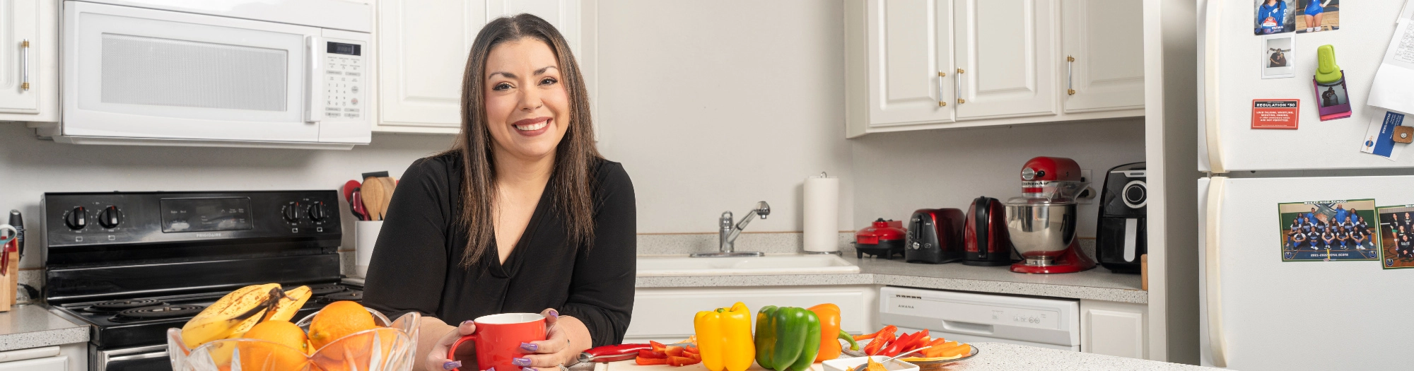 Ahappywomanstandinginherkitchenholdingacoffeemugandsmiling