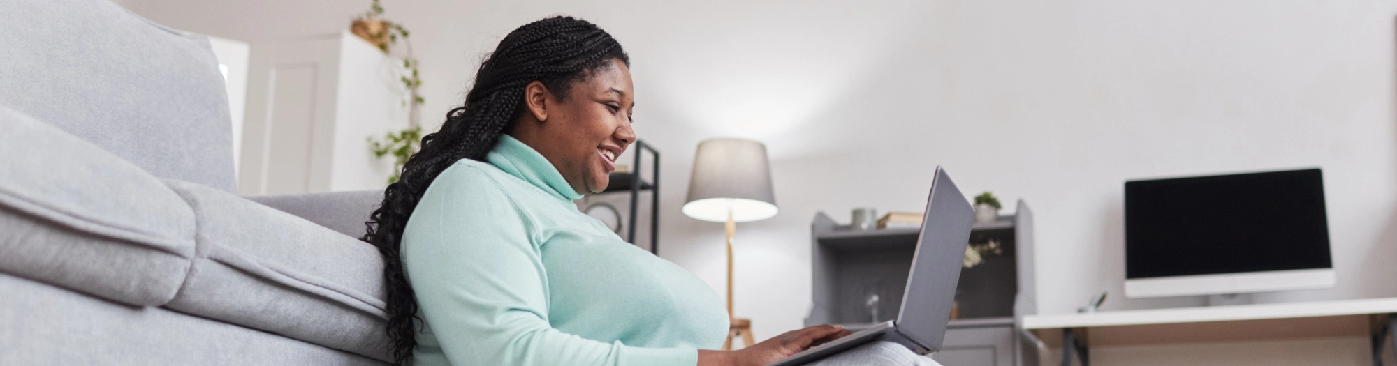 Womansittingonthelivingroomfloorwithalaptoponherlap