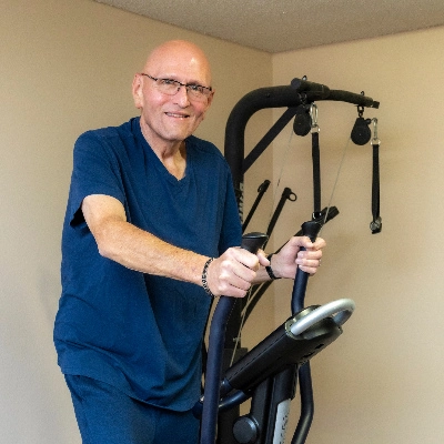Man in a gym using an eliptical machine.
