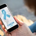 PersonholdingsmartphonewithCancerDayonscreen