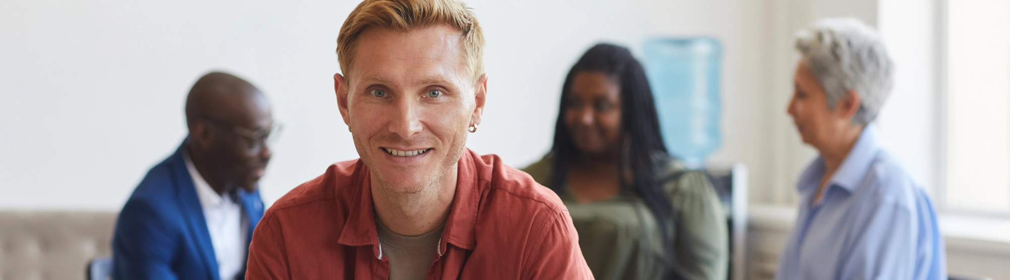 Mansmilingatcamerawithsupportgrouphappeninginthebackground