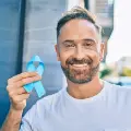 Manstandingoutsideholdingablueprostatecancerribbon