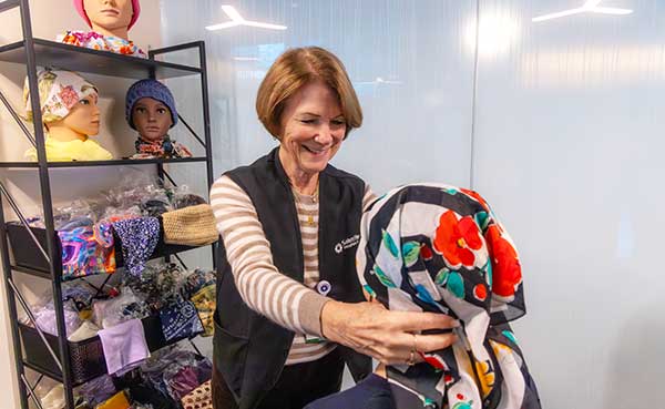 Sue placing a headscarf on a cancer patient