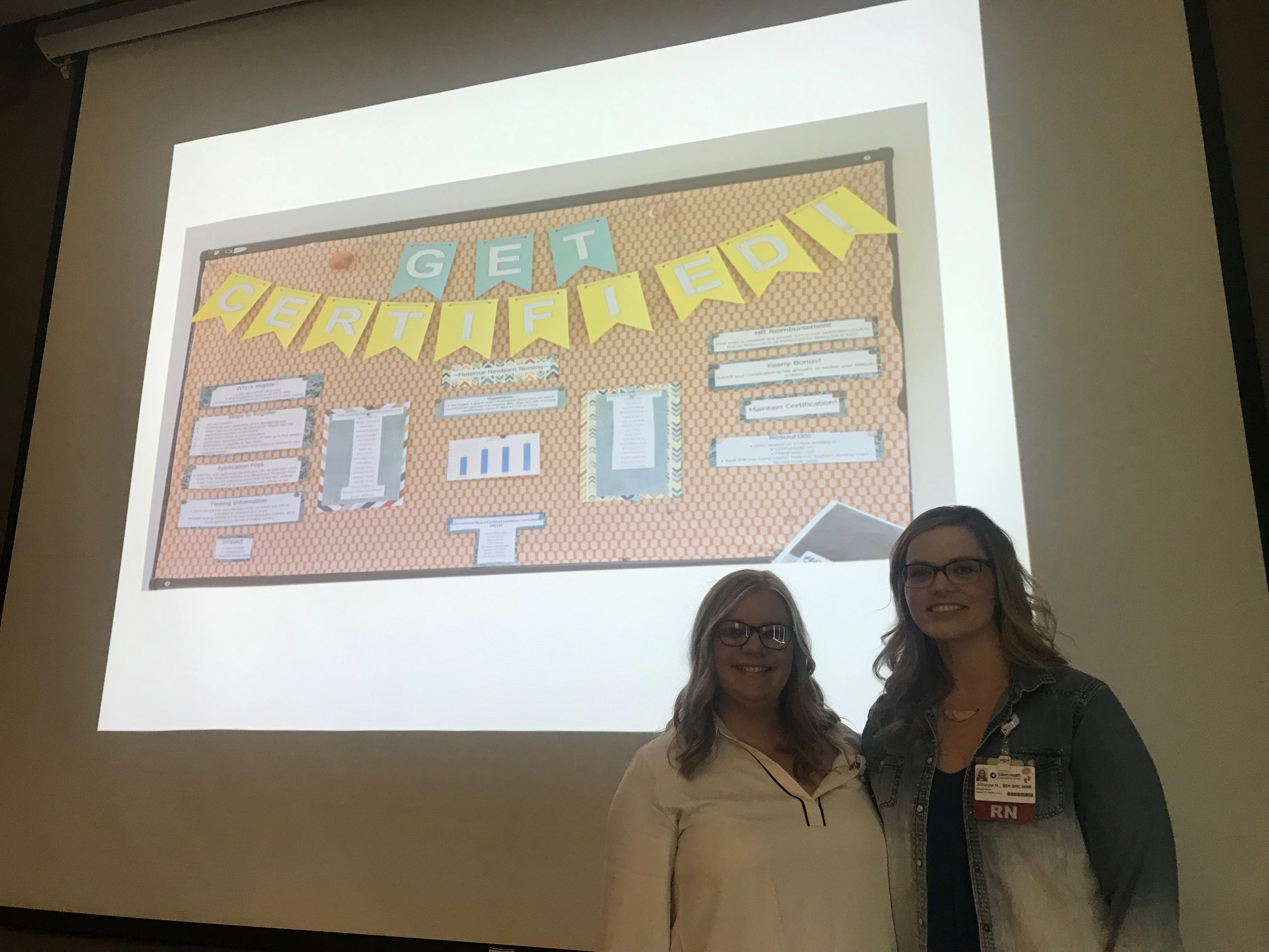 TwowomenstandingbyascreendisplayingaslideforMBUcertification