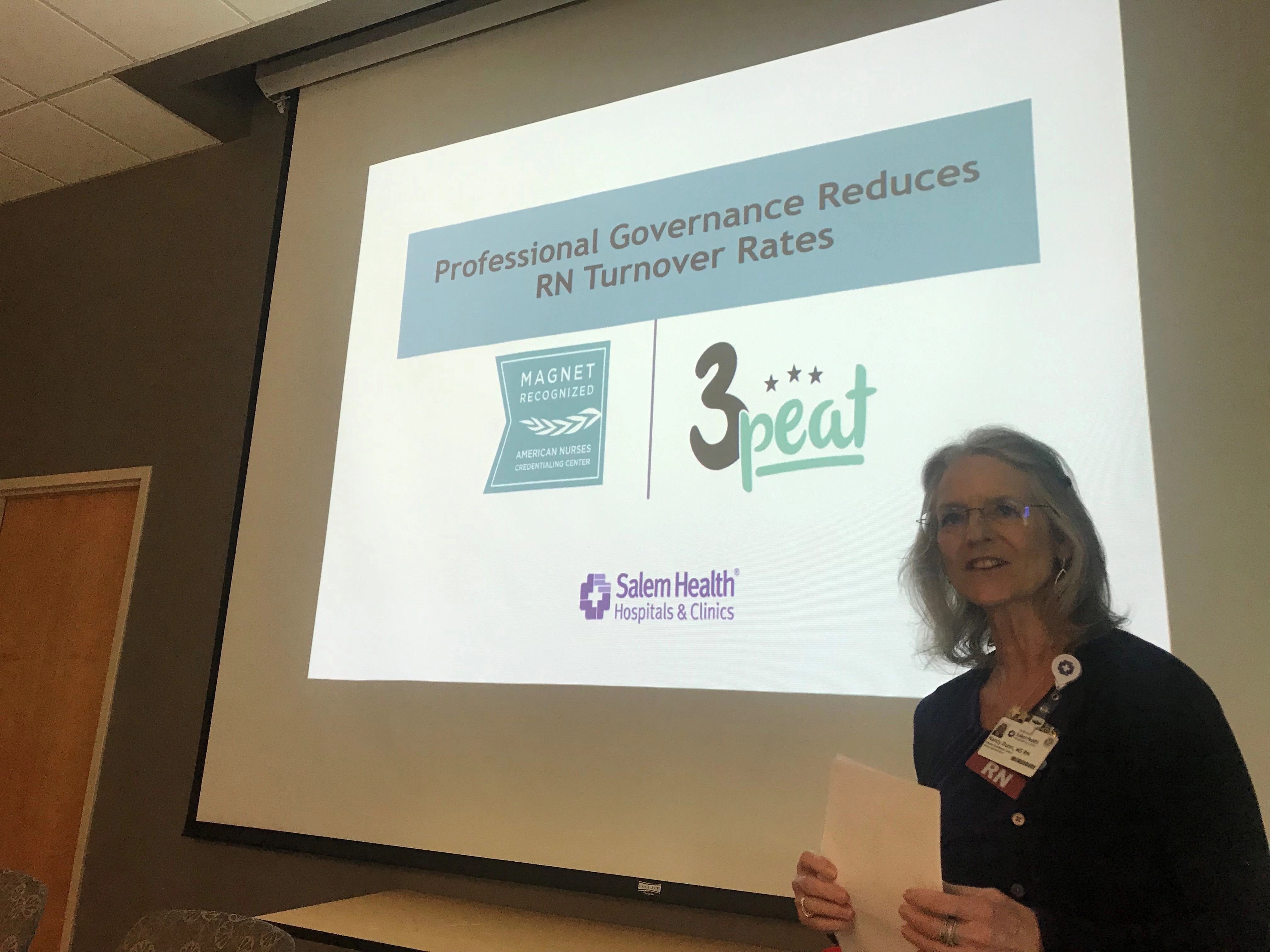 AwomanstandingbyascreendisplayinganRNturnoverrateslide