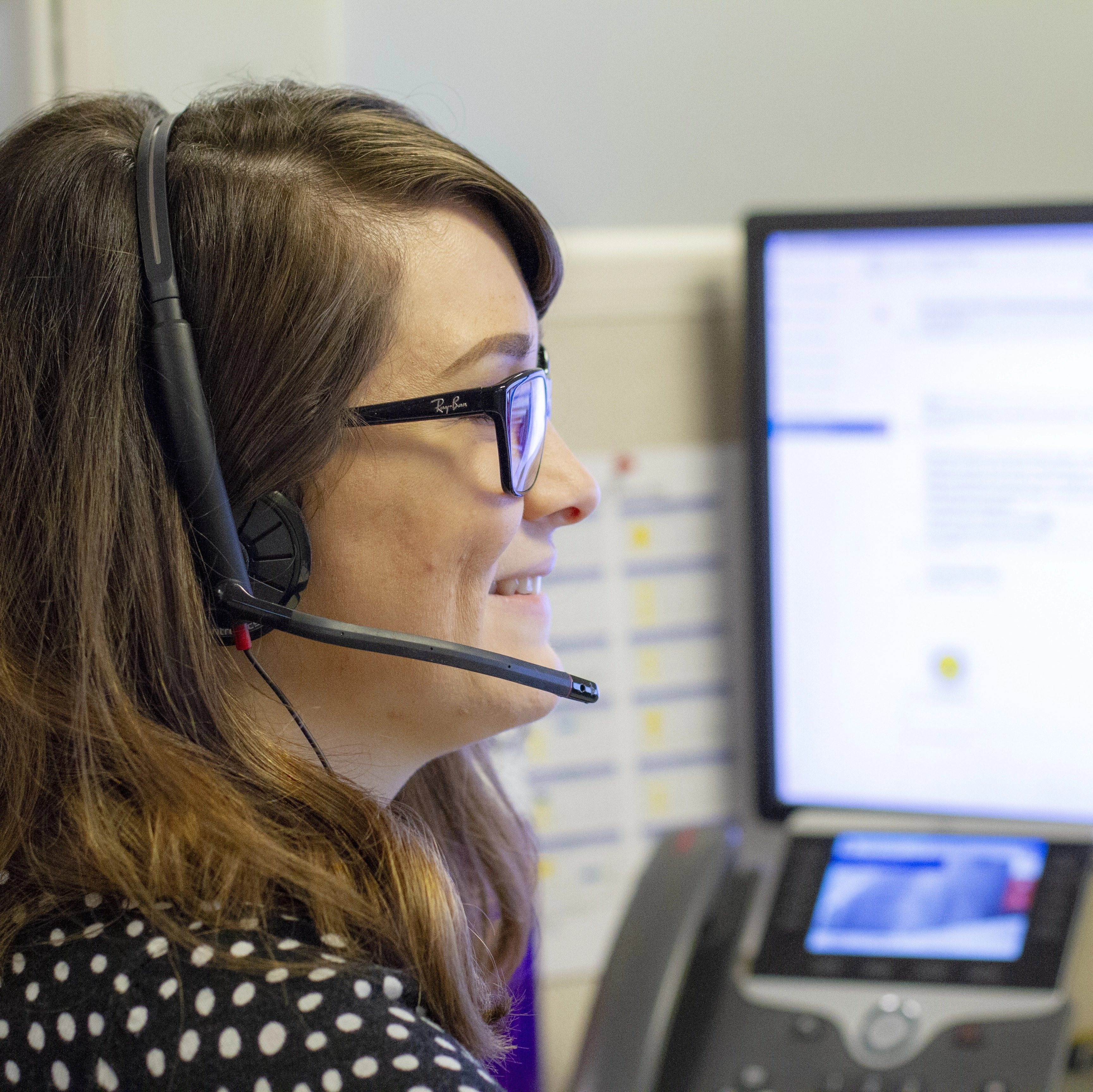 FemaleISoperatorwithheadsetandcomputerscreeninthebackground