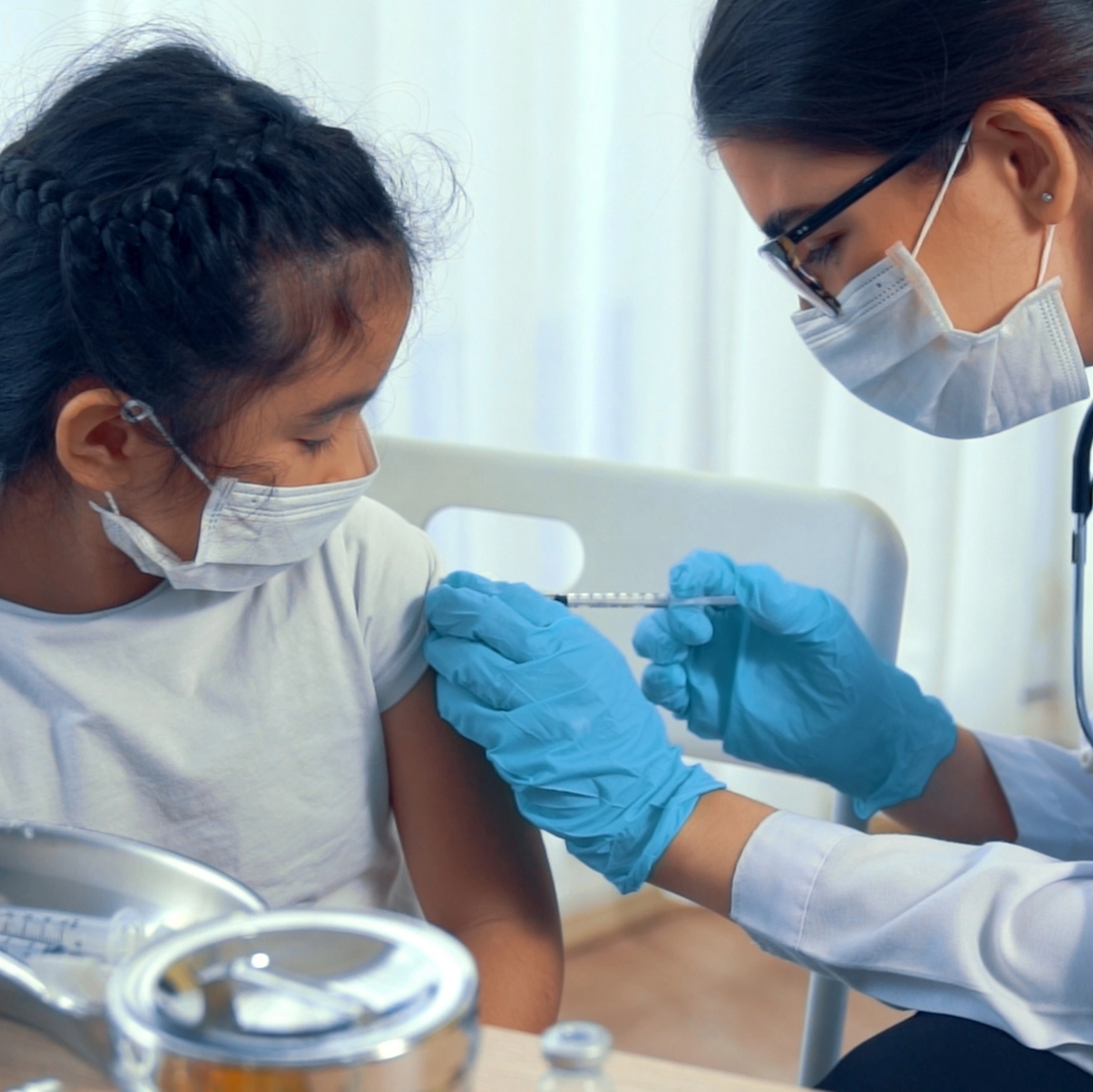 Darkhairedfemaleprovidergivesvaccinationtobrownhairslittlegirl