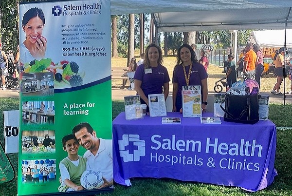TwoSalemHealthCHECstaffersstandingbehindaninformationtableatarecentcommunityevent