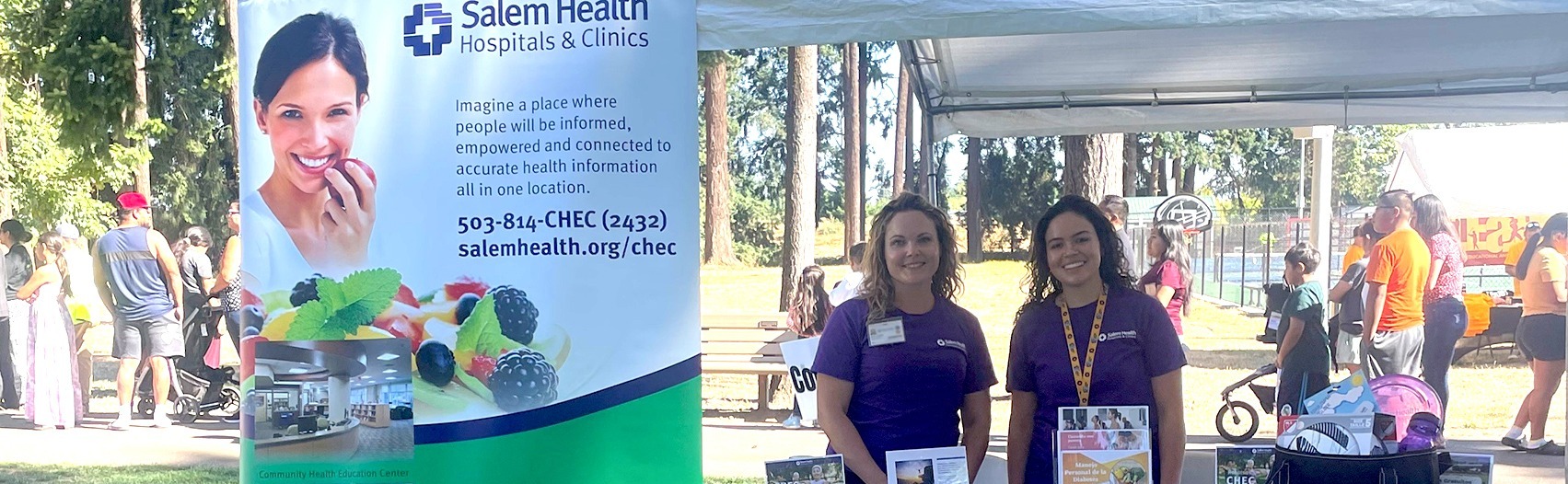 TwoSalemHealthCHECstaffersstandingbehindinfotableatcommunityevent