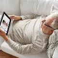 Anoldermanreclinesonhiscouchwhilevideochattingwithadoctor