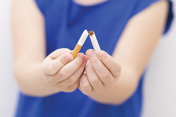 Close-upimageofawomanbreakinghercigaretteinhalf