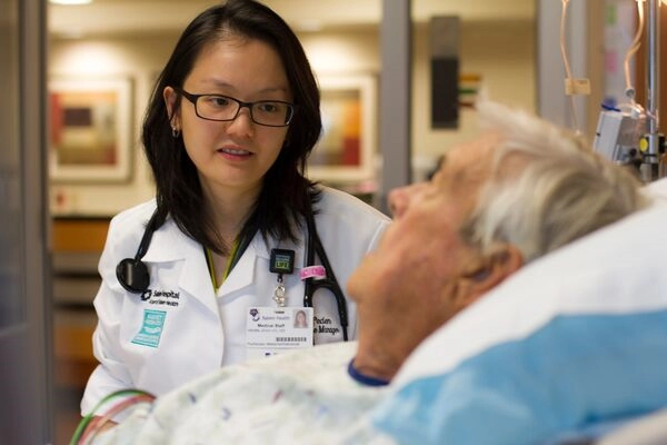 Doctor talking with a patient who is recovering in a hospital bed