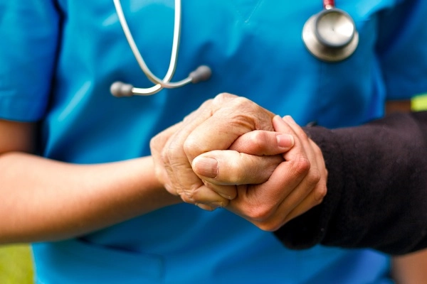 Anurseinbluescrubsholdthehandofanelderlyperson