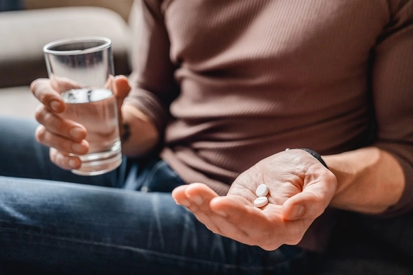 Medication management program - A man holds aspirin and a glass of water