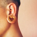 Closeupofagaugedearwithalargewoodenplugwithaheartonit