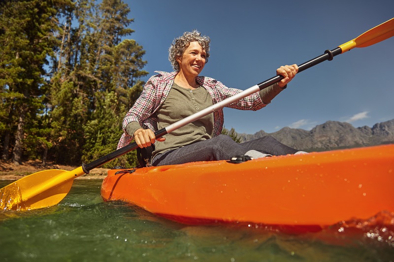 Athletic woman kayaking at the lake on a summer day