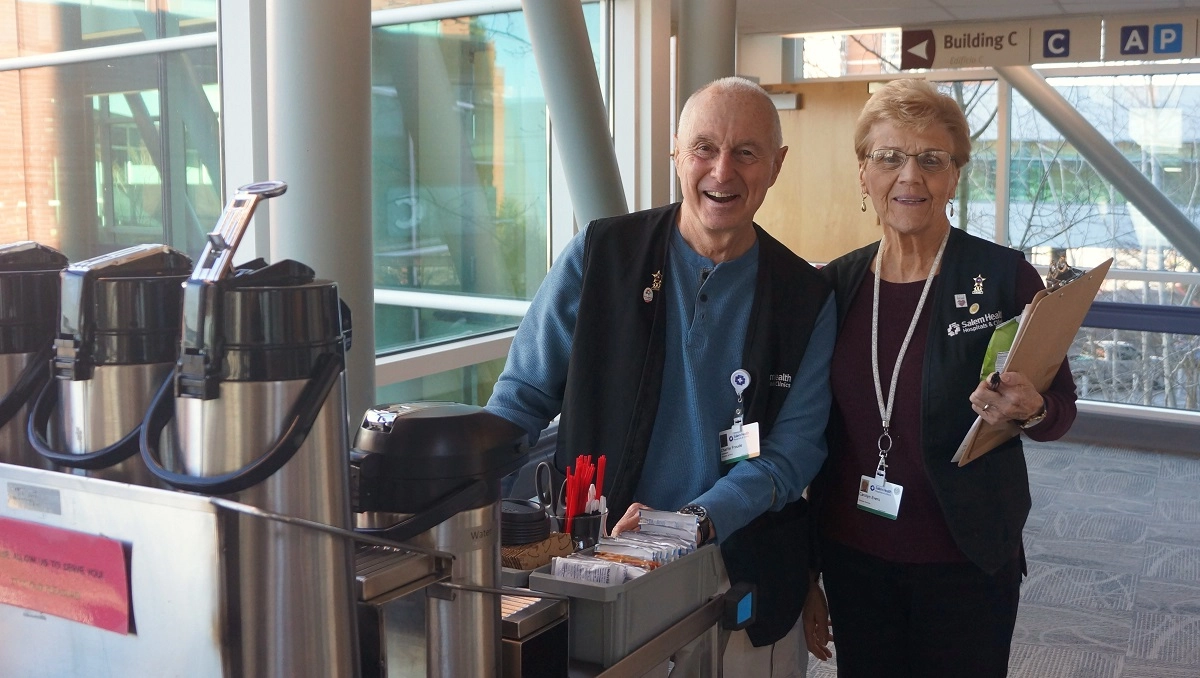 coffee cart resized Adult volunteers pushing a cart with coffee urns through Salem Hospital.
