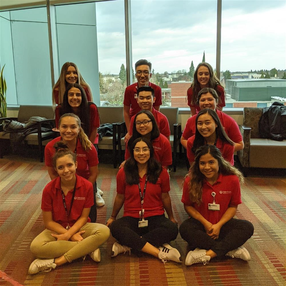 Students Twelve formed students wearing red shirts smile at the camera