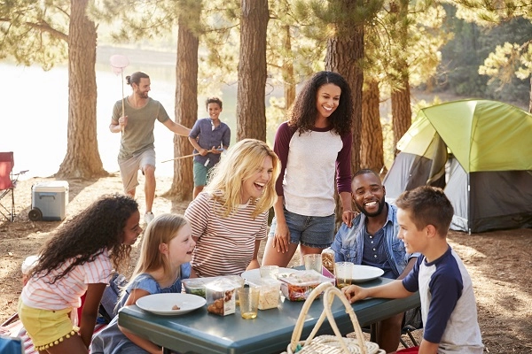 Two families eating at a picnic table in a campground.