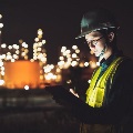 Asianmanengineerusingdigitaltabletworkinglatenightshiftatoilrefineryinindustrialpark