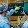Teamofdoctorsstudydigitalmonitorastheyperformhipreplacementsurgeryinsidetheoperatingroom