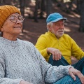 Oldmanandwomaninsweatersmeditatingandrelaxinginthemountainsoutdoors