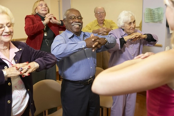 Five people with hands clasped and elbows in the air, following an instructor.