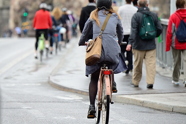 Awomanonabikewithamessengerbagcommutingwithotherbikers