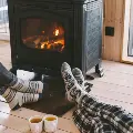 Closeupphotoofhumanfeetinwarmwoolensocksoverfireplace
