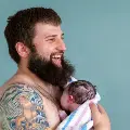 Youngmanwithbeardandtattoosholdinganewborn