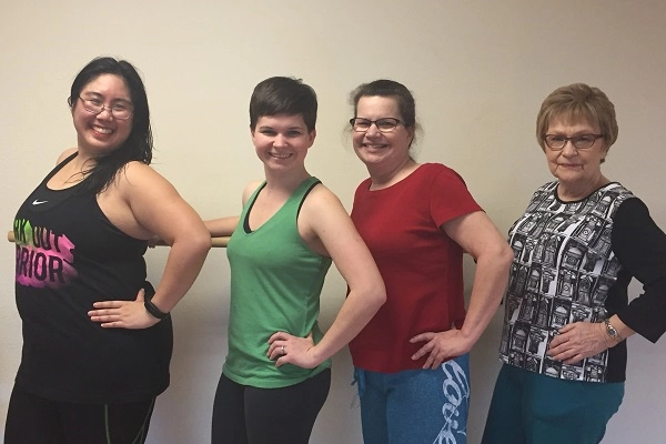 Afitnessinstructorposeswithamulti-generationalfamilyforazumbaclass