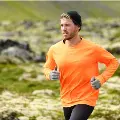 Maninorangeshirtrunningoutdoors