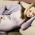 Pregnantwomansleepingonhersideonacouchwithonehandonherstomach